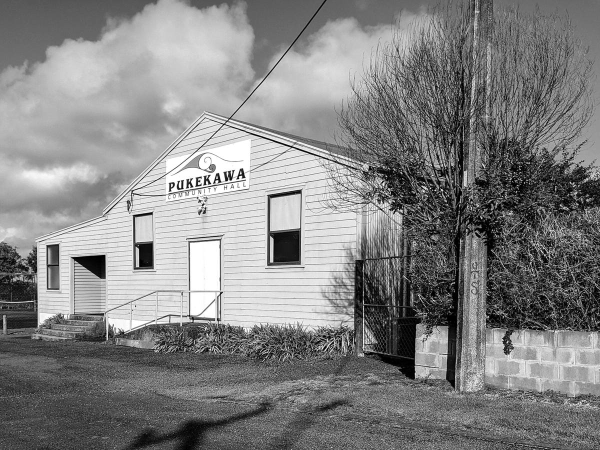A weatherboard community hall with a sign on its gable